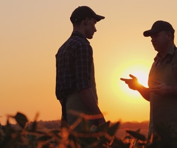 Two men discussing at sunset, in a field