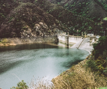 A one sided view of a dam with water and a vegetation around it